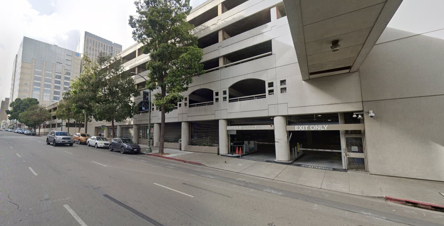 Street-level view of a downtown parking garage beside a wide sidewalk.
