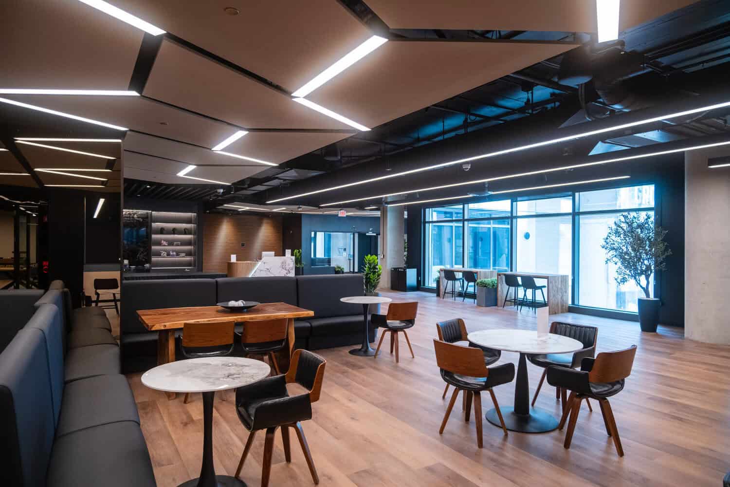 Open lounge area with tables, chairs, and geometric ceiling lights.