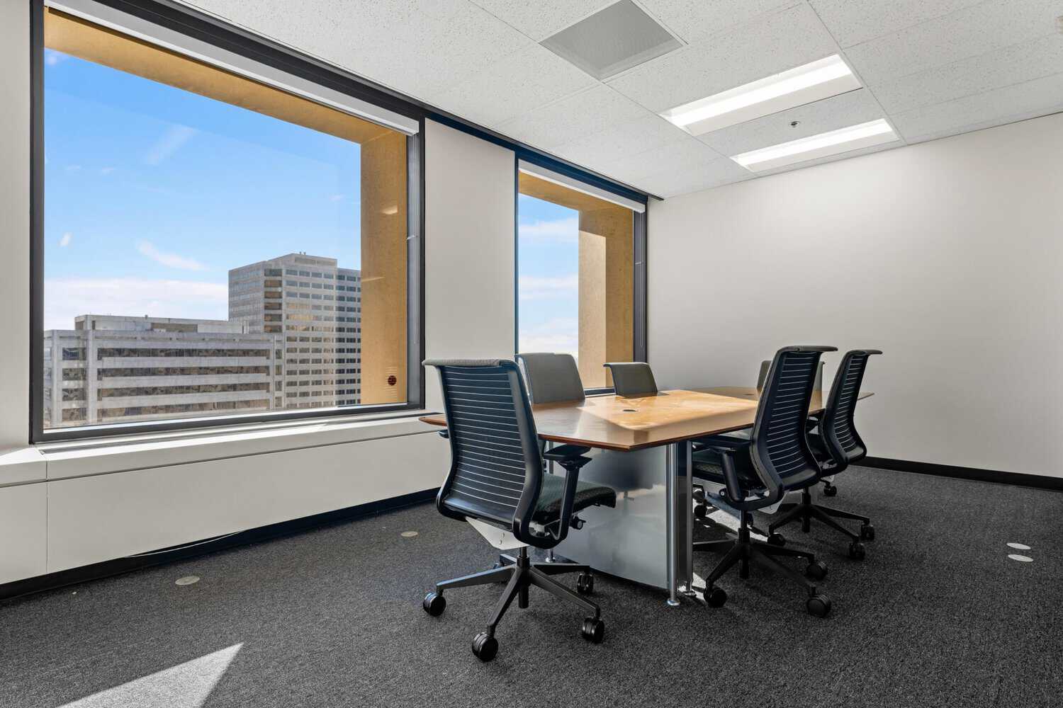 Private office with table, chairs, and large city-facing window.