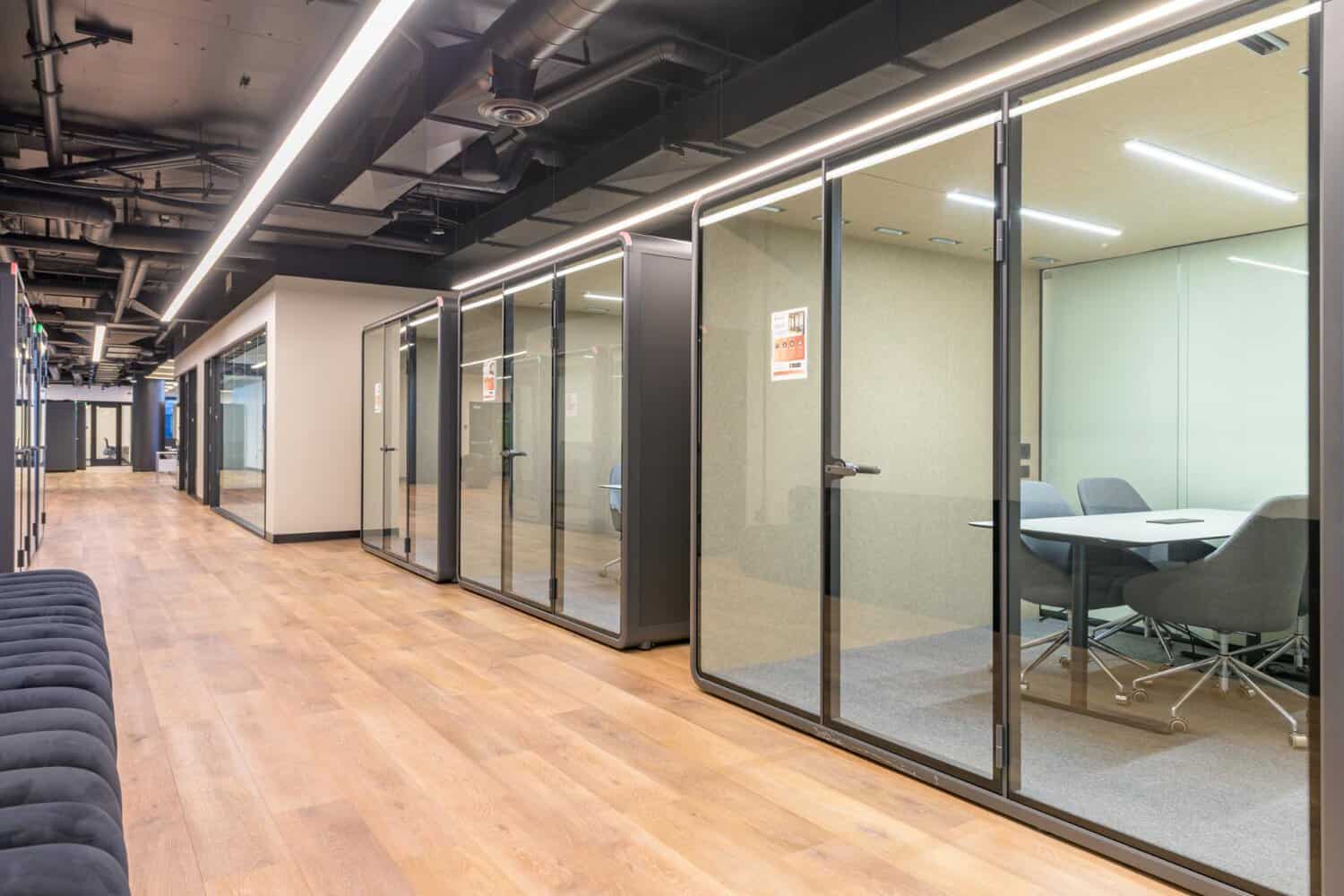 Glass-walled phone booths and pods along a STAK Space corridor in Oakland