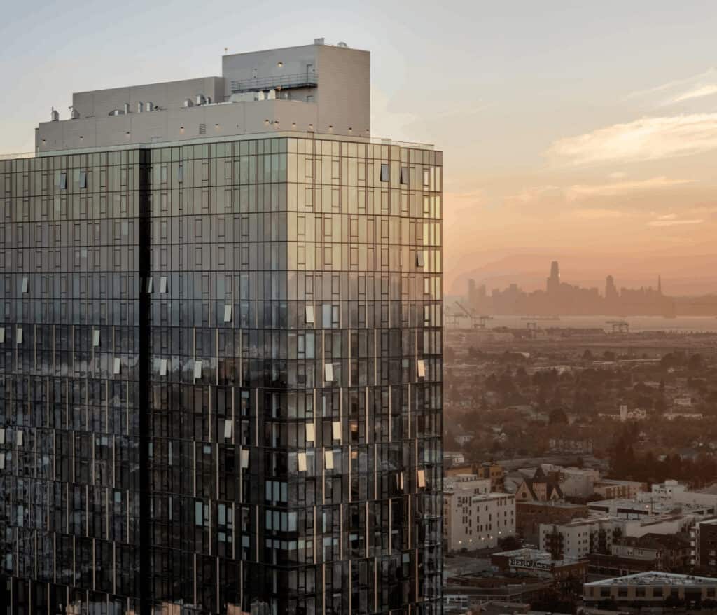 1900 Broadway tower at sunset with Oakland skyline in the distance.