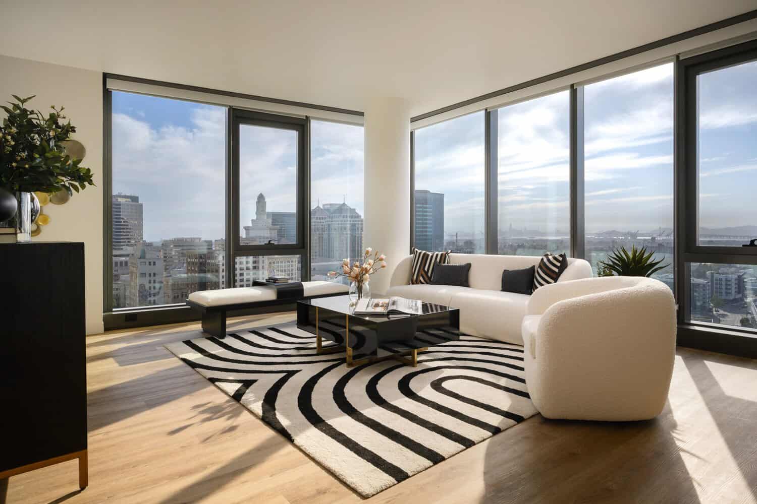Living room with a sofa, dining table and large windows in a two-bedroom apartment at 1900 Broadway