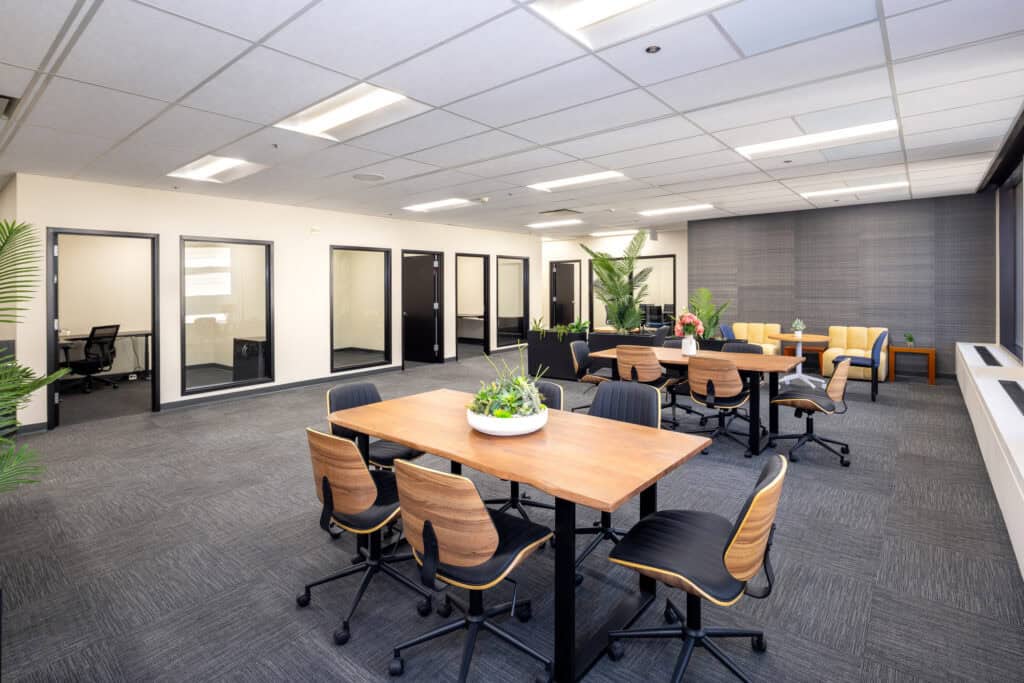 Open work area with wood tables and private offices in a Level 4 office suite in Oakland