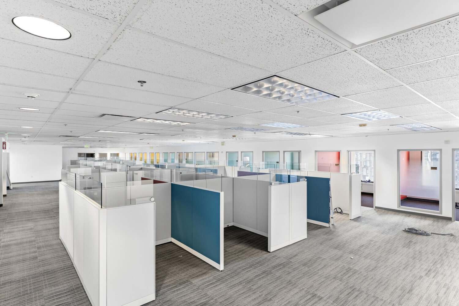 Long rows of cubicles with blue panels and private offices along the windows at 1950 Franklin