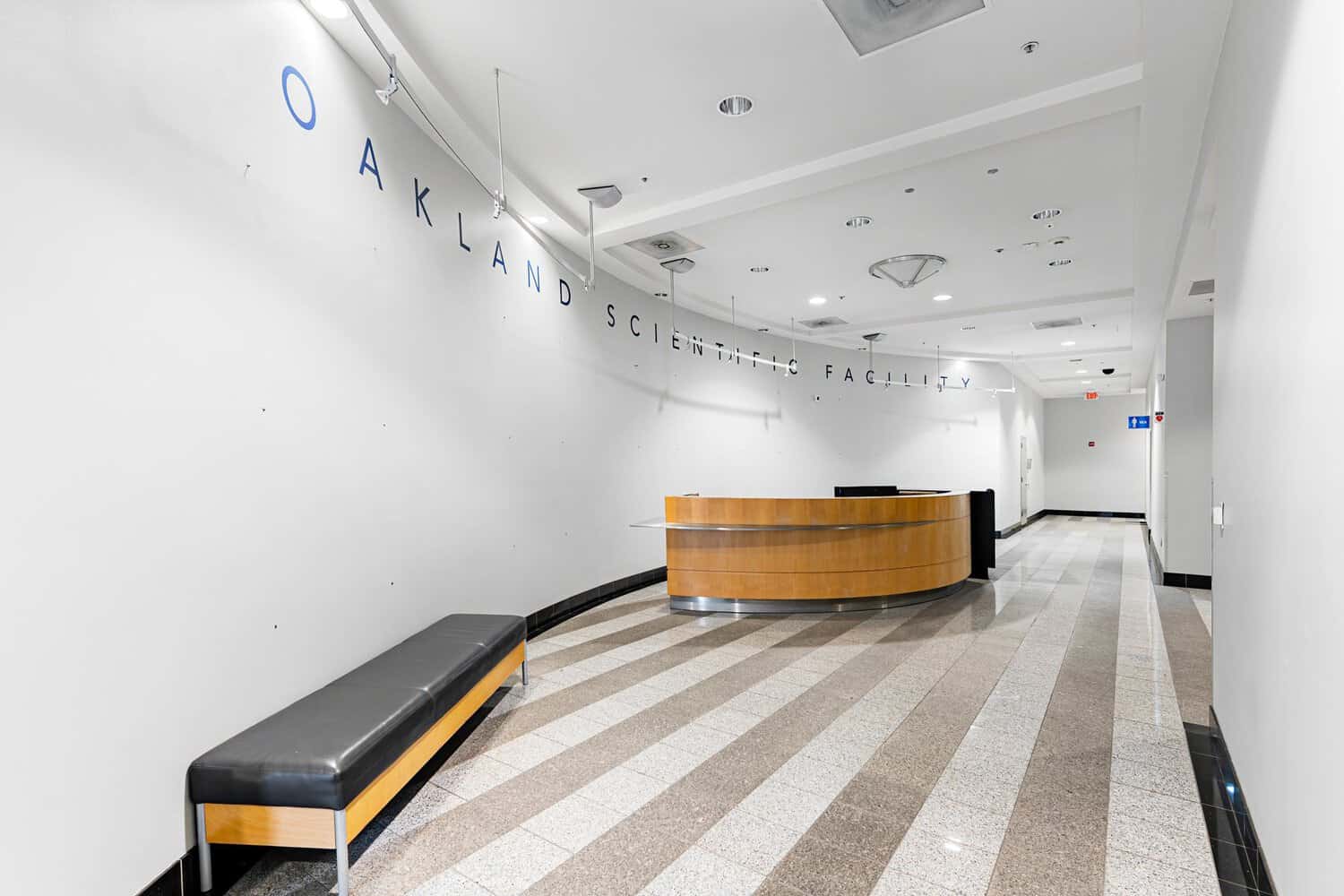 Retro building lobby with curved wood reception desk and striped stone floor at 415 20th Street