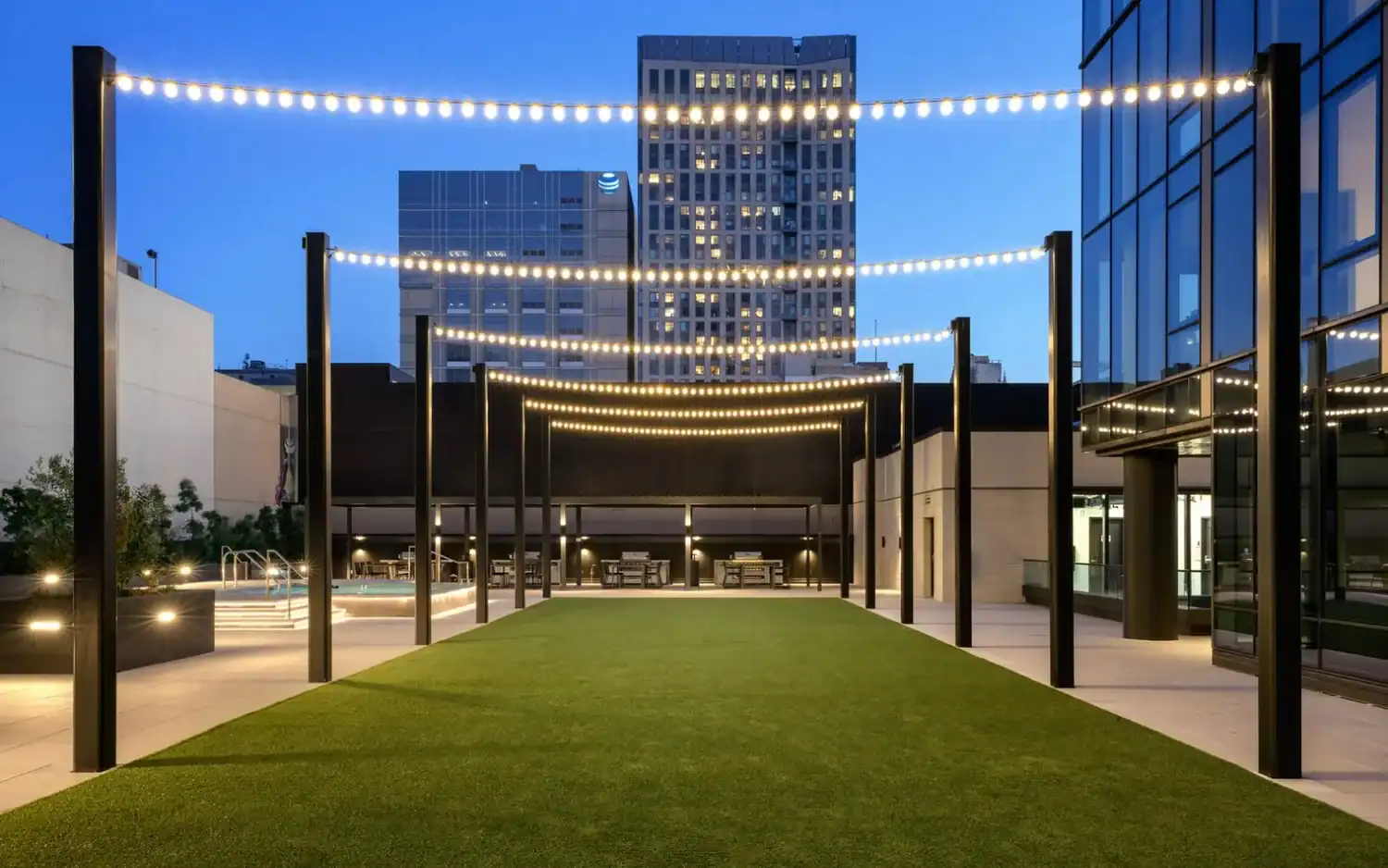 Outdoor podium deck with string lights and lawn at dusk at 1900 Broadway